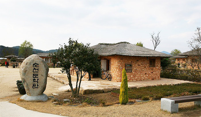 순천문학관 전경 사진으로 돌에 순천문학관이 적혀 있고, 뒷 배경으로 순천문학관이 보인다